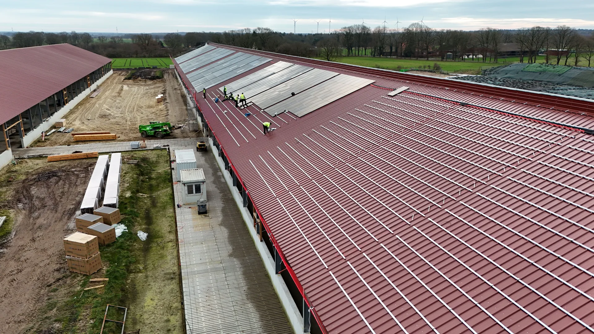 Montageteam bei der Modulinstallation auf dem roten Trapezdach, Schienensystem sichtbar